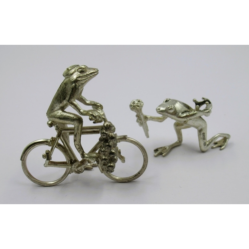 1047 - Two unusual silver figures of frogs, one on a bicycle and one holding a torch