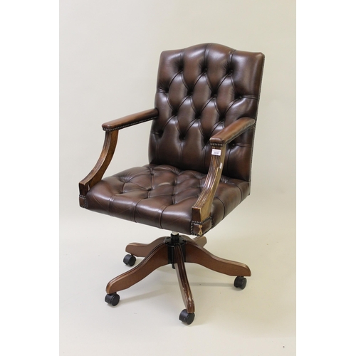 Reproduction mahogany and brown button leather upholstered swivel armchair