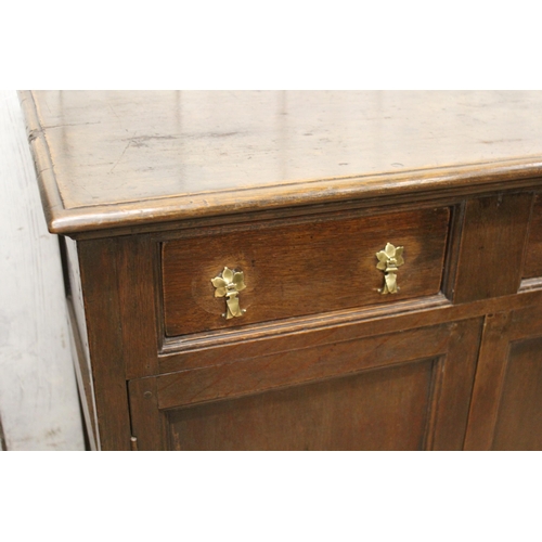 1439 - Oak dresser base, the moulded top above three short drawers with brass drop handles, with two panell... 