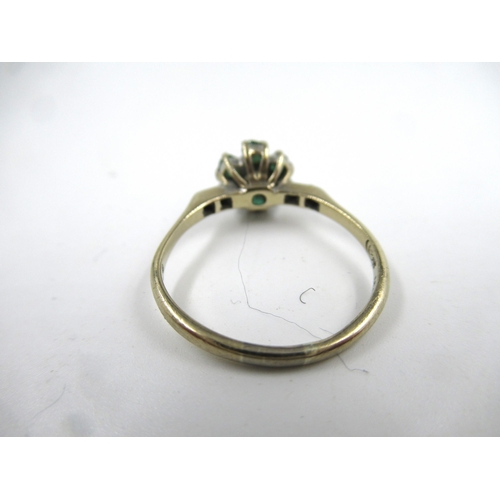 606 - 18ct Gold emerald and diamond flowerhead ring with diamond set shoulders, 2.7g