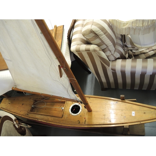 160 - Large scale wooden pond yacht with sail, the hull painted in orange on a later stand, 207cm long