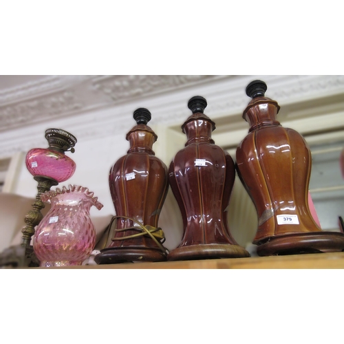 379 - Three matching pottery brown glazed floral decorated lamp bases and an oil lamp with glass well and ... 