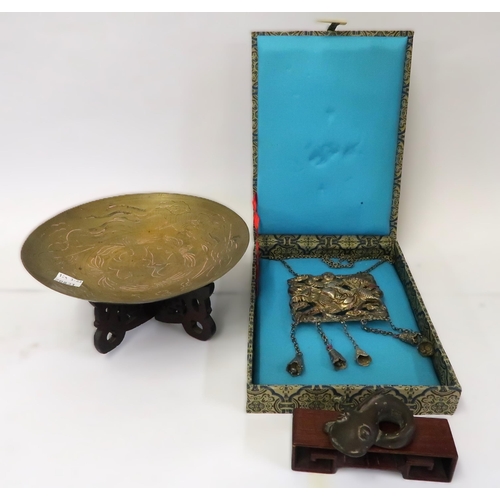 97 - Chinese white metal pendant in a silk covered box, together with a small Chinese brass dish on a woo... 