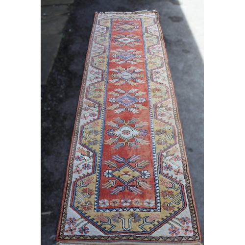 19 - Modern Turkish runner with a repeating medallion design on a peach ground with borders, 287 x 85cm