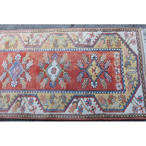 19 - Modern Turkish runner with a repeating medallion design on a peach ground with borders, 287 x 85cm