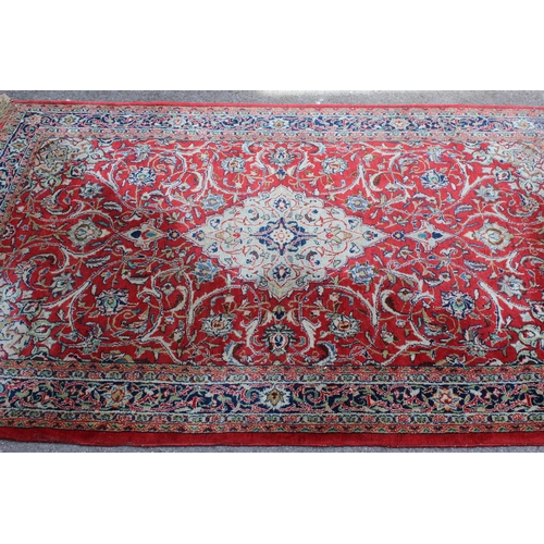 28 - Sarouk rug with central medallion and multiple borders on a red ground, 132 x 218cm