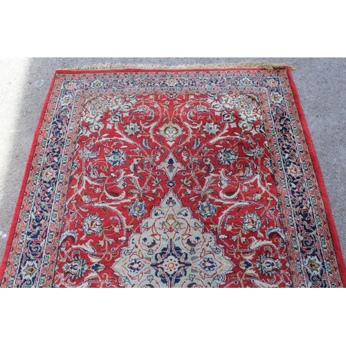 28 - Sarouk rug with central medallion and multiple borders on a red ground, 132 x 218cm