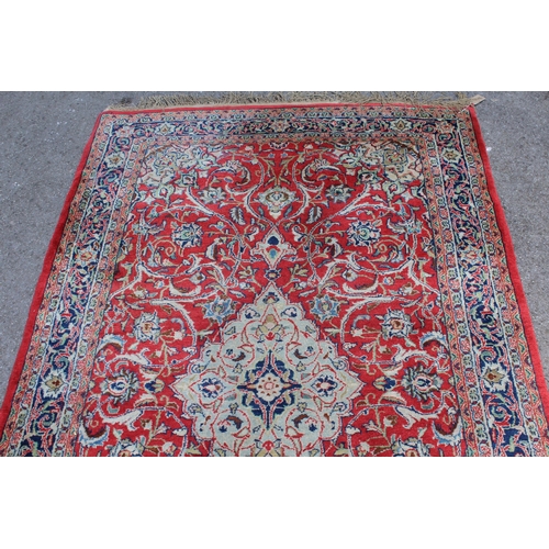 28 - Sarouk rug with central medallion and multiple borders on a red ground, 132 x 218cm