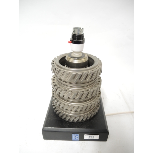 395 - Modern table lamp constructed from gear box cog wheels, the ebonised plinth base with Rolls Royce la... 