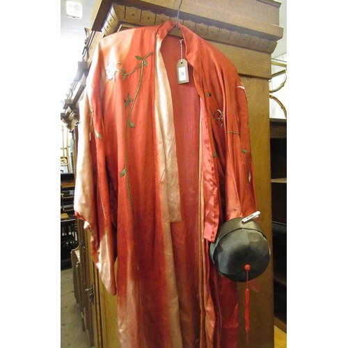 31 - Chinese red silk kimono with embroidered floral decoration, together with a hat (sun damaged)