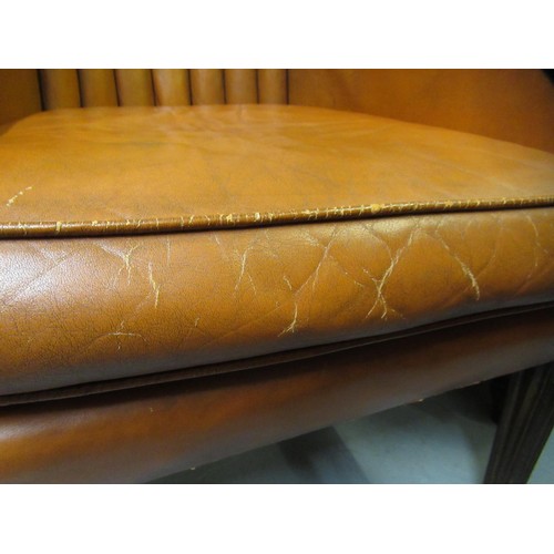 1960 - Mid 20th Century mid tan leather upholstered barrel back wing arm chair, on square tapering supports