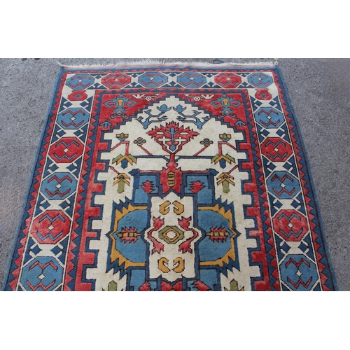 10 - Kazak rug having all-over geometric design with borders on a red, blue and cream ground, 1.5m x 2.3m