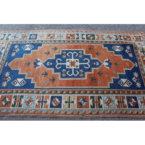 11 - Kazak rug having central medallion on an orange and blue ground with borders, 132 x 235cm