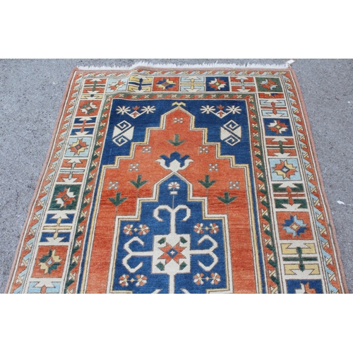 11 - Kazak rug having central medallion on an orange and blue ground with borders, 132 x 235cm