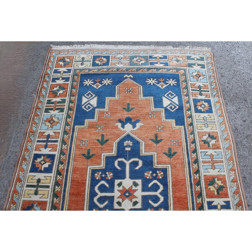 11 - Kazak rug having central medallion on an orange and blue ground with borders, 132 x 235cm