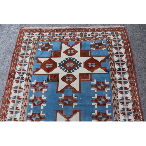 12 - Kazak rug having two hooked medallions on a cream and pale blue ground with multiple borders, 1.5 x ... 