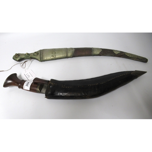 284 - Early 20th Century kukri with carved wooden handle and leather sheath, together with a Middle Easter... 