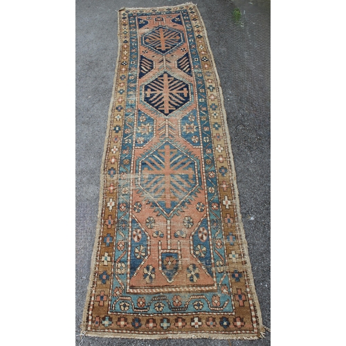 3 - Kurdish runner with a triple medallion design on a terracotta ground with borders (worn), 270 x 70cm