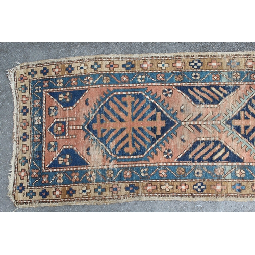 3 - Kurdish runner with a triple medallion design on a terracotta ground with borders (worn), 270 x 70cm