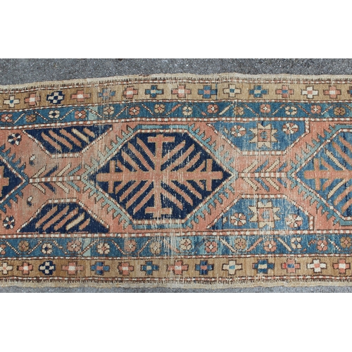 3 - Kurdish runner with a triple medallion design on a terracotta ground with borders (worn), 270 x 70cm