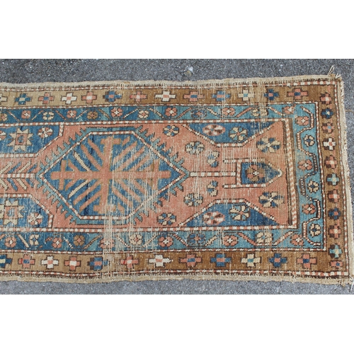 3 - Kurdish runner with a triple medallion design on a terracotta ground with borders (worn), 270 x 70cm