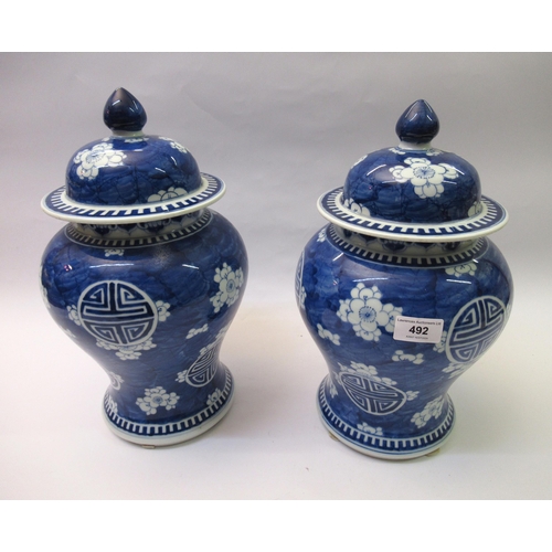 492 - Pair of Chinese blue and white prunus blossom decorated baluster form vases with covers, 36cm high