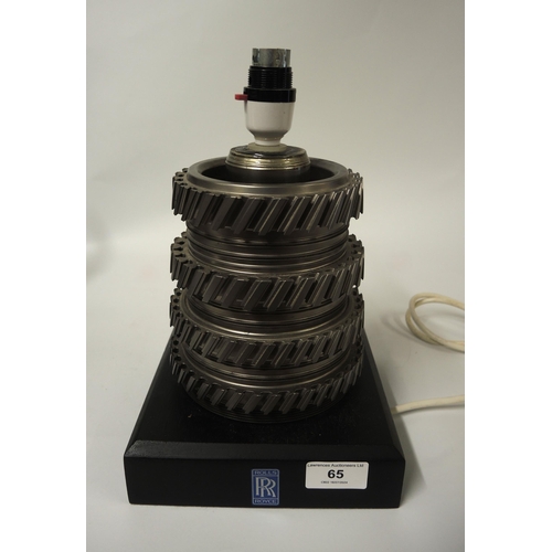 65 - Modern table lamp constructed from gear box cog wheels, the ebonised plinth base with Rolls Royce la... 