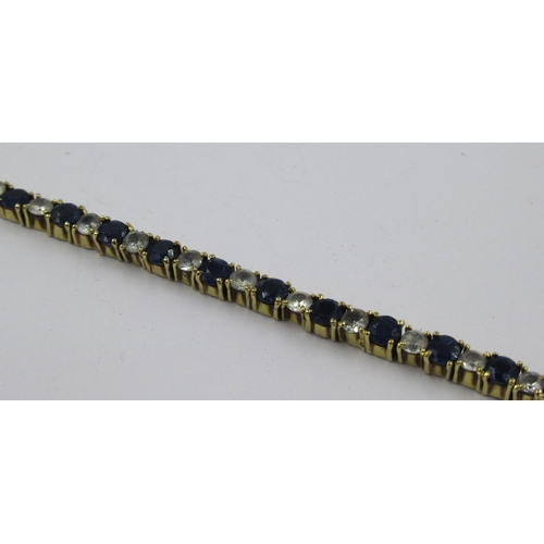 723 - 18ct Yellow gold blue and white sapphire line bracelet, 9.5g