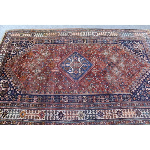 12 - Qashqai rug with a hooked centre medallion and all-over stylised floral design on a red ground with ... 