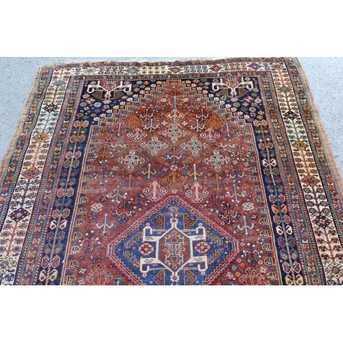 12 - Qashqai rug with a hooked centre medallion and all-over stylised floral design on a red ground with ... 