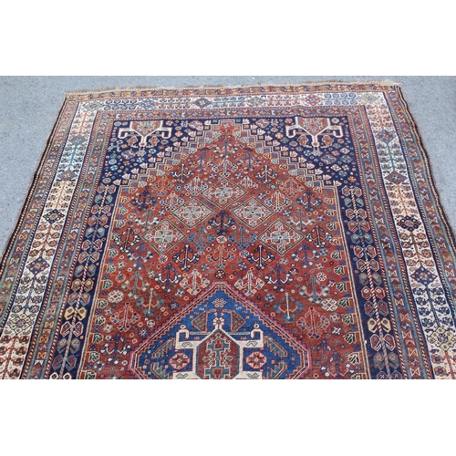 12 - Qashqai rug with a hooked centre medallion and all-over stylised floral design on a red ground with ... 