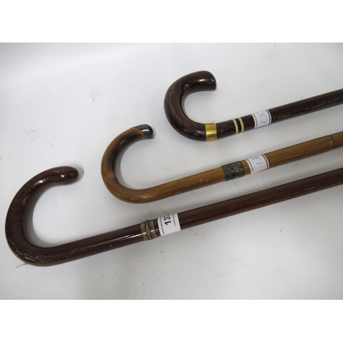 137 - Two walking canes with silver collars, together with another with gilt metal collar