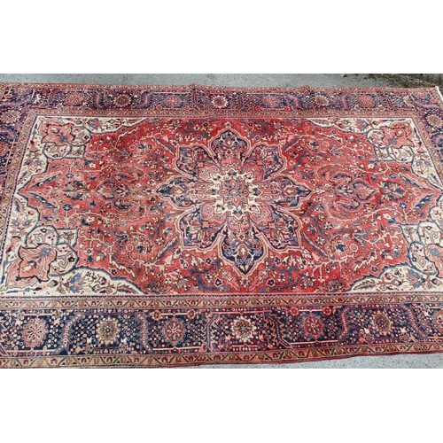 14 - Heriz carpet with a lobed medallion and all-over stylised floral design on a red ground with cream g... 