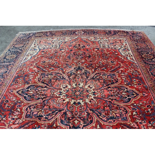 14 - Heriz carpet with a lobed medallion and all-over stylised floral design on a red ground with cream g... 