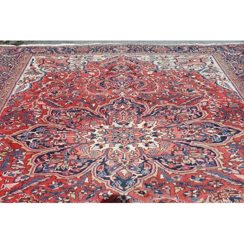 14 - Heriz carpet with a lobed medallion and all-over stylised floral design on a red ground with cream g... 