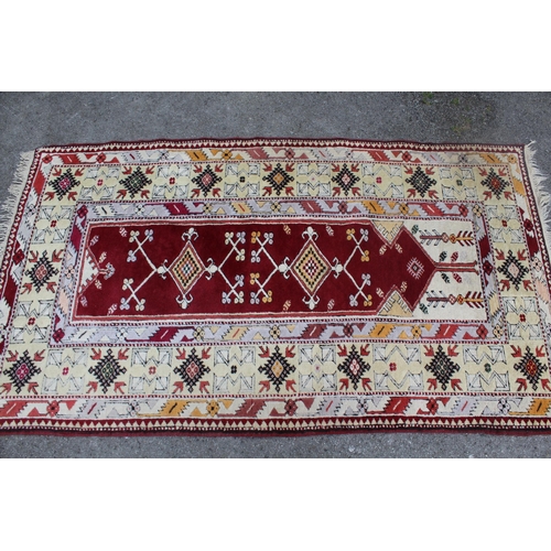 22 - Turkish rug of Persian design with a central Mihrab on a red ground with ivory borders, 198 x 113cm