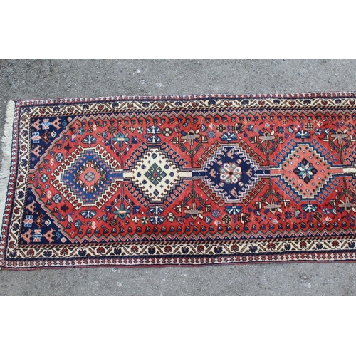 27 - Small Kurdish runner with a linked hooked medallion design on a rose ground with borders, 192 x 65cm