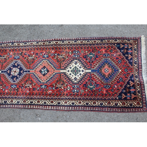 27 - Small Kurdish runner with a linked hooked medallion design on a rose ground with borders, 192 x 65cm