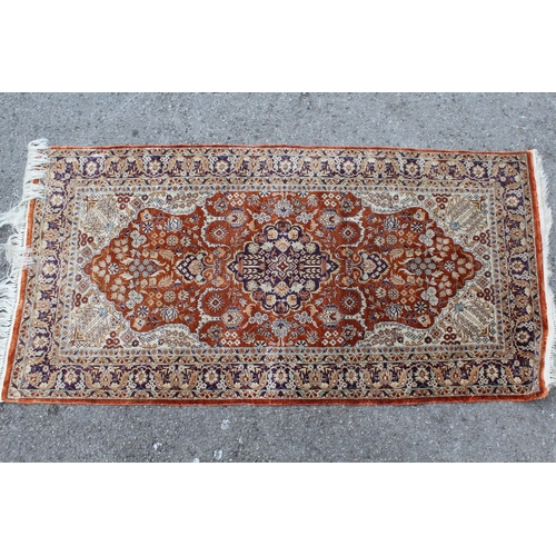 33 - Small Turkish silk style rug with a medallion and floral design on a terracotta ground borders, 120 ... 