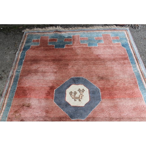 13 - Gabbeh style rug with a centre medallion and plain rust ground with borders, 229 x 168cm