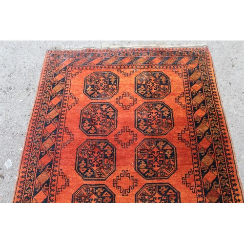 15 - Afghan rug with two rows of five gols on a red ground, 182 x 125cm