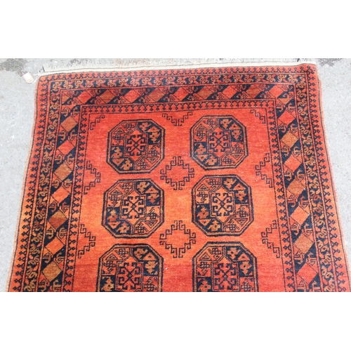 15 - Afghan rug with two rows of five gols on a red ground, 182 x 125cm