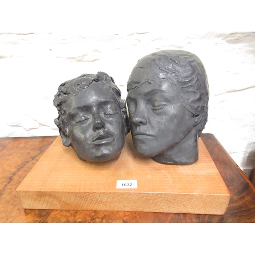 1632 - Two black painted pottery head studies of a mother and child sleeping mounted on a  wooden plinth