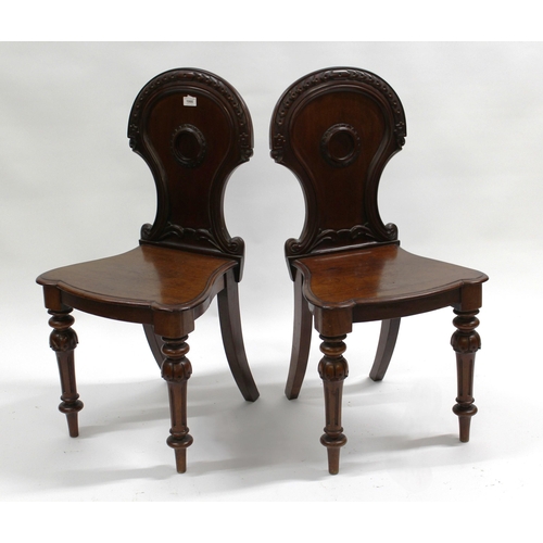 1990 - Pair of Victorian mahogany hall chairs, the shaped carved backs above panel seats and turned fluted ... 