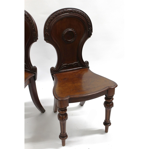 1990 - Pair of Victorian mahogany hall chairs, the shaped carved backs above panel seats and turned fluted ... 