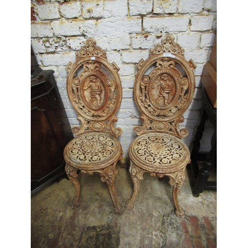 2011 - Pair of heavy painted cast iron garden chairs, the oval backs cast with figures