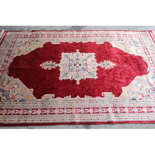 21 - Pakistan rug with a lobed medallion and plain design on a burgundy ground with borders, 255 x 158cm