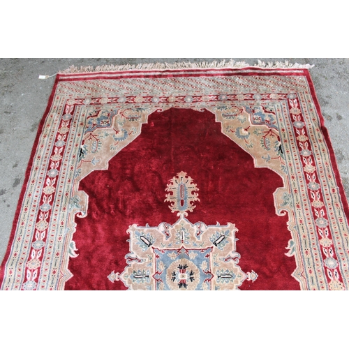 21 - Pakistan rug with a lobed medallion and plain design on a burgundy ground with borders, 255 x 158cm