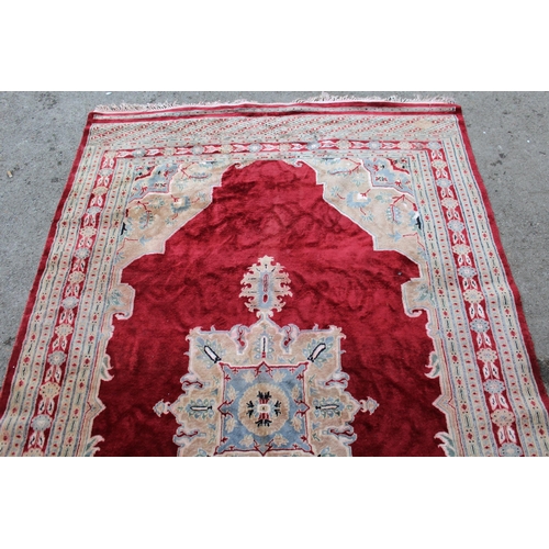 21 - Pakistan rug with a lobed medallion and plain design on a burgundy ground with borders, 255 x 158cm