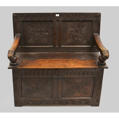 1966 - 17th Century and later oak hall bench, the panelled back with carved arm rests and hinged seat, on s... 